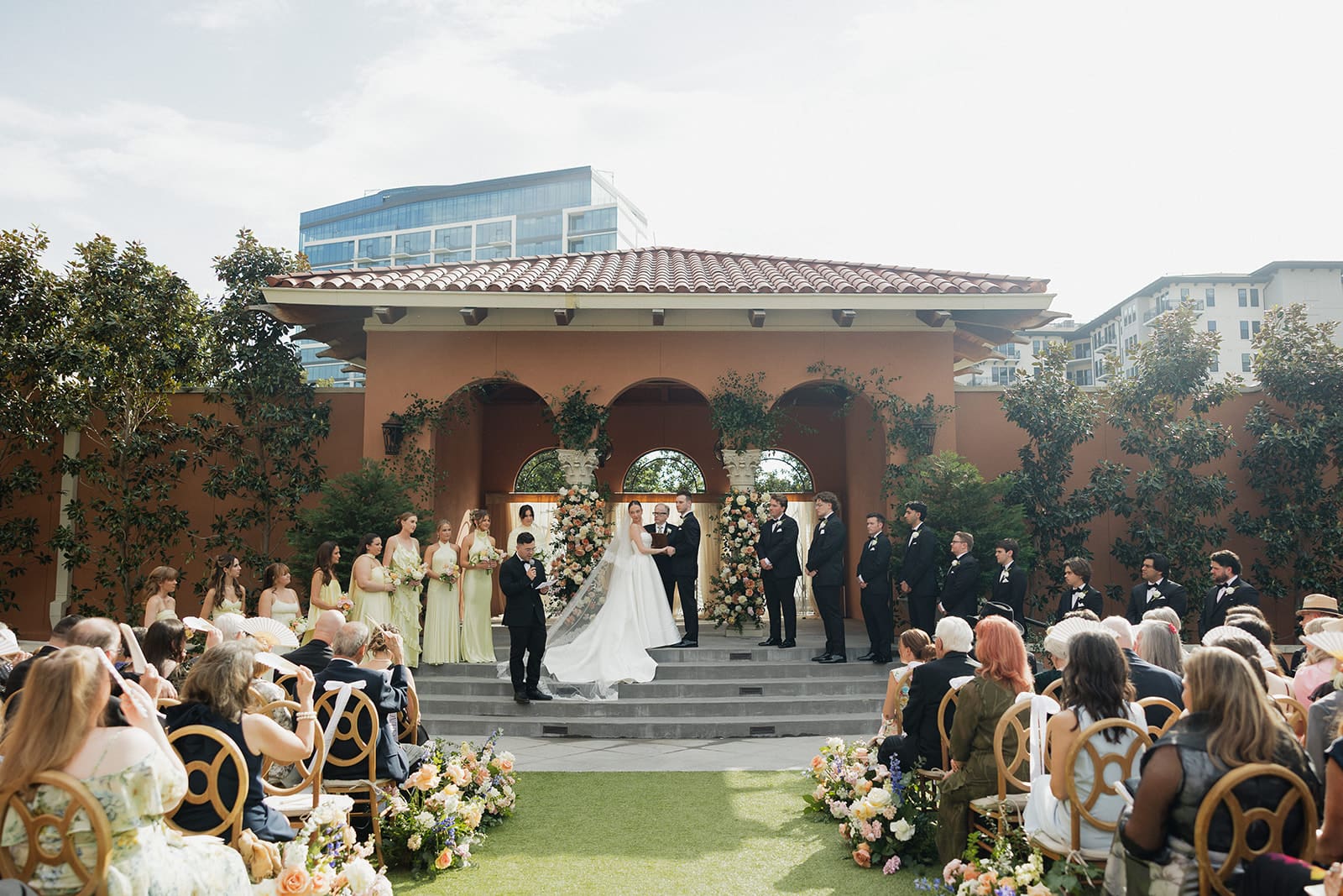 Outdoor wedding ceremony at a Mediterranean-style Dallas venue as the bride enters the aisle