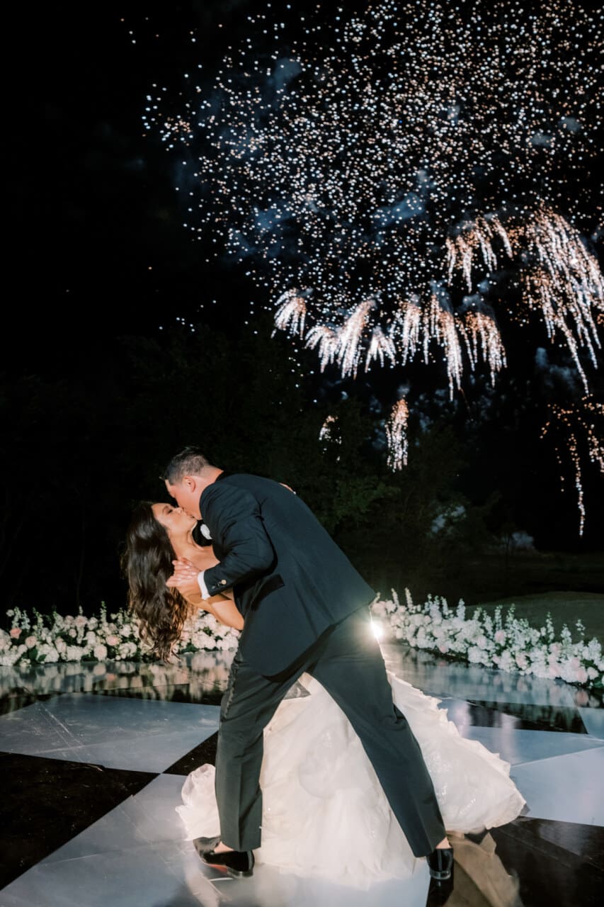 Nighttime sparkler send-off as the couple shares a poolside embrace