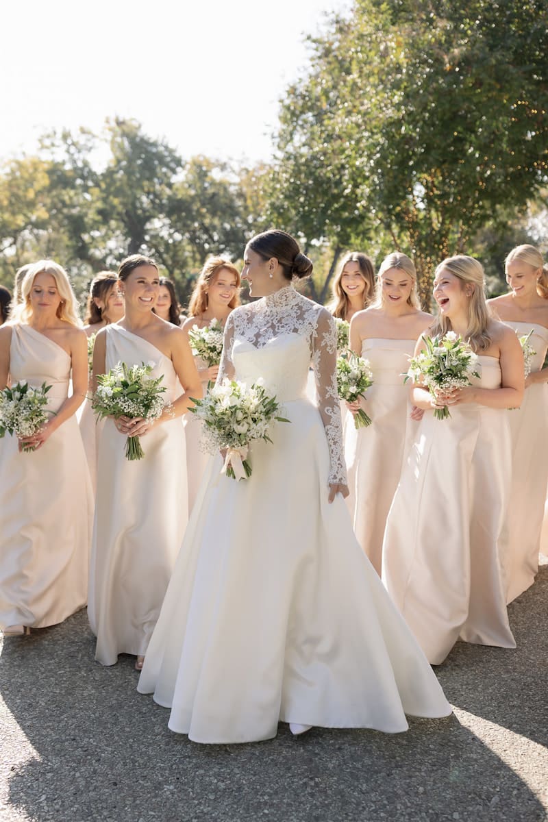 Bride with her wedding party in champagne gowns walking through the grounds